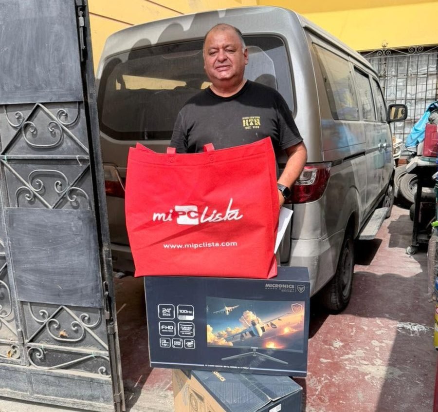 Cliente con la bolsa de su compra y la caja de su monitor en la puerta de la tienda
