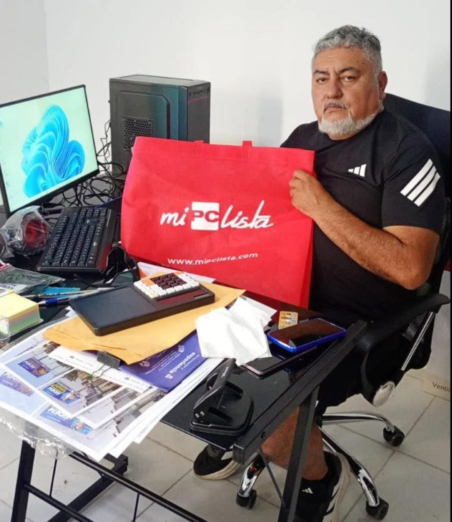 Cliente sentado en su escritorio con la bolsa de su compra junto a su PC